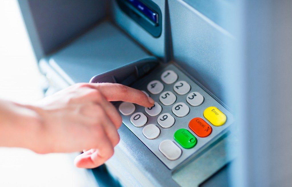 Hand entering PIN on ATM machine