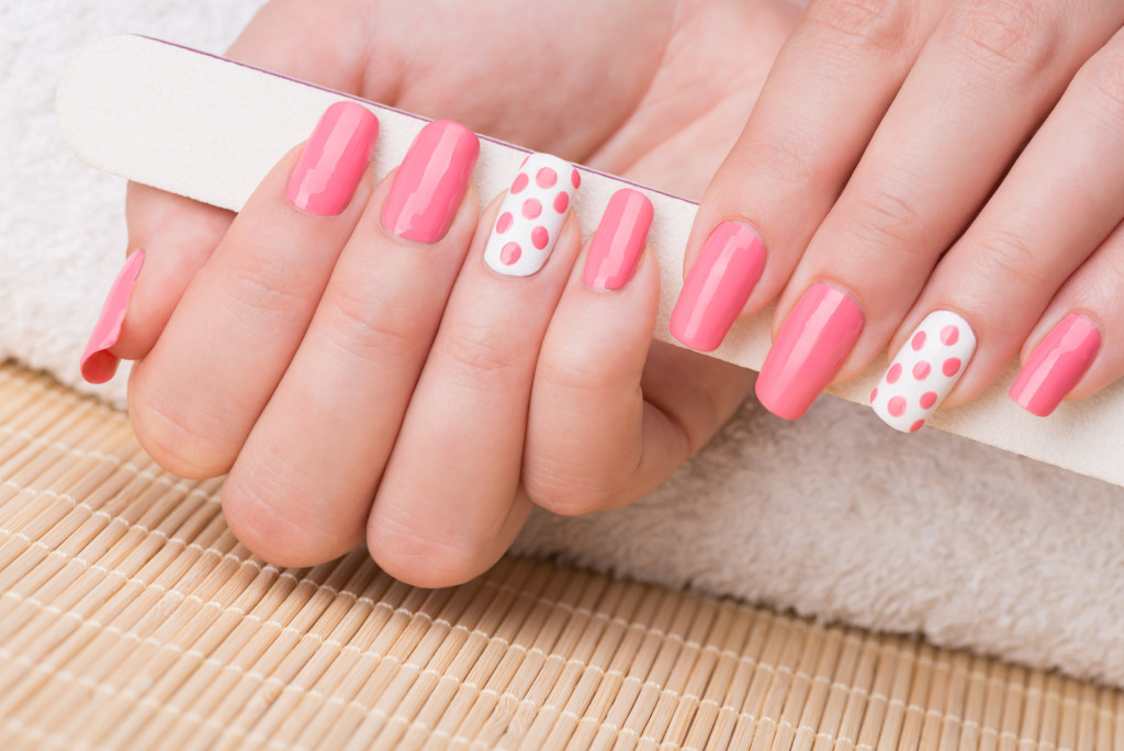 Manicure - Beauty treatment photo of nice manicured woman fingernails holding nail file