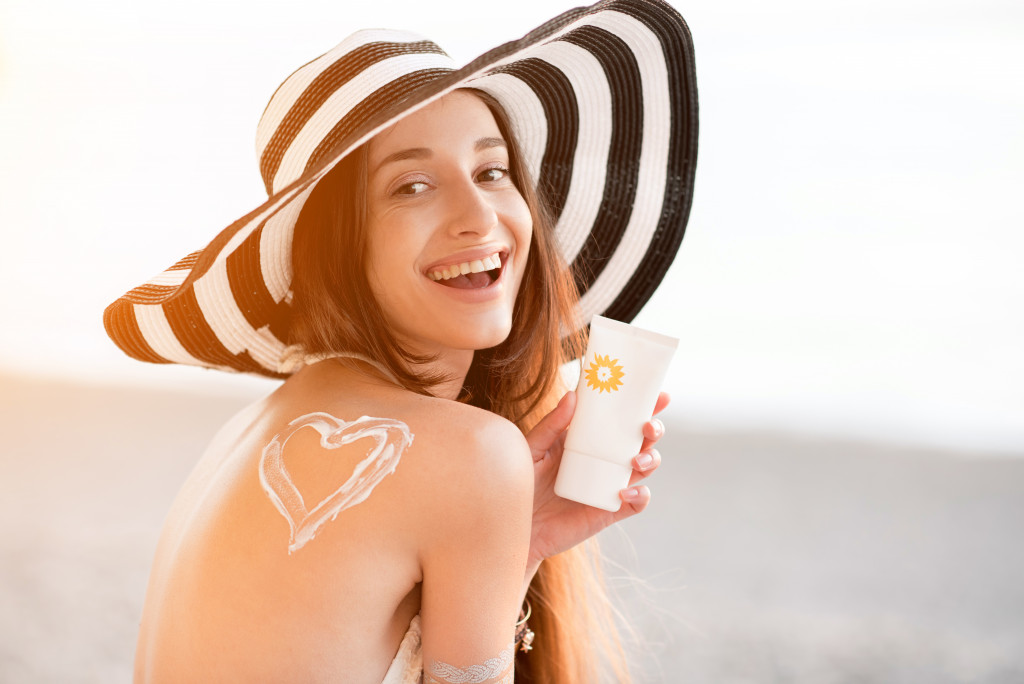 young woman in a hat holding sunscreen