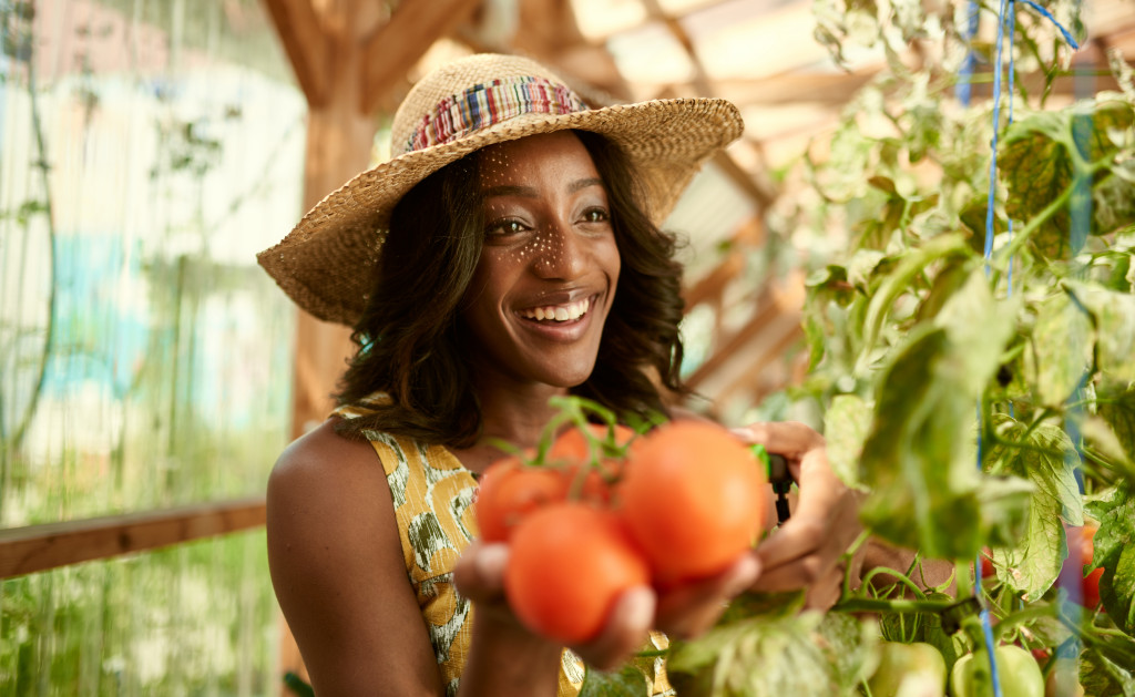 beautiful smiling woman with hat holding ripe tomatoes for purchase in a local shop